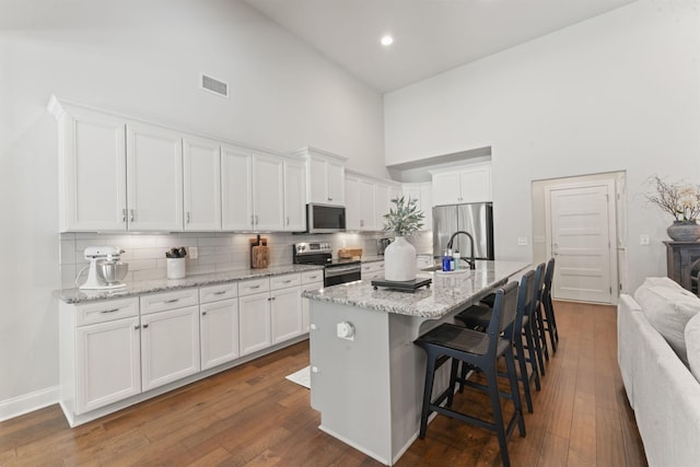 239 Mcclaran Pl, Murfreesboro, TN 37129 - kitchen with appliances with stainless steel finishes, high vaulted ceiling, tasteful backsplash, white cabinetry, and dark wood-style floors