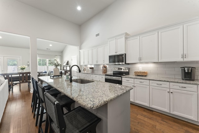 239 Mcclaran Pl, Murfreesboro, TN 37129 - kitchen featuring stainless steel appliances, white cabinetry, a high ceiling, decorative backsplash, and a breakfast bar area