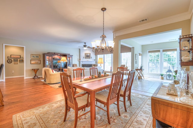 507 Bugler Rd, Mount Juliet, TN 37122 - dining space featuring a fireplace, a chandelier, light wood-style flooring, ornamental molding, and a ceiling fan
