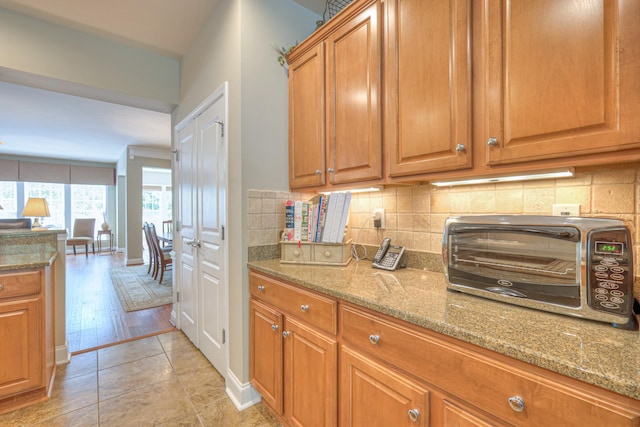 507 Bugler Rd, Mount Juliet, TN 37122 - kitchen featuring light stone counters, decorative backsplash, brown cabinets, and light tile patterned flooring