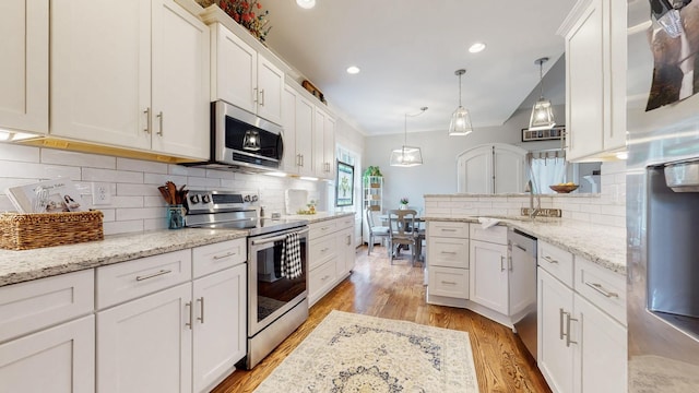 7146 Pepper Tree Cir, Fairview, TN 37062 - kitchen with appliances with stainless steel finishes, light wood-style flooring, white cabinetry, backsplash, and a peninsula