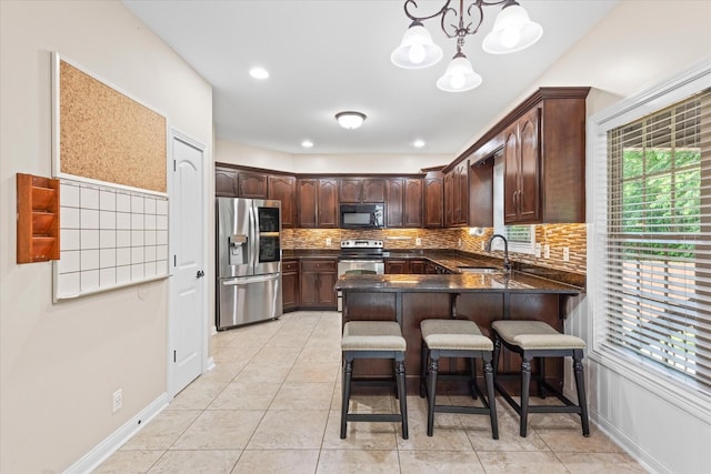 1741 Apache Way, Clarksville, TN 37042 - kitchen featuring appliances with stainless steel finishes, a peninsula, dark brown cabinetry, a breakfast bar, and tasteful backsplash