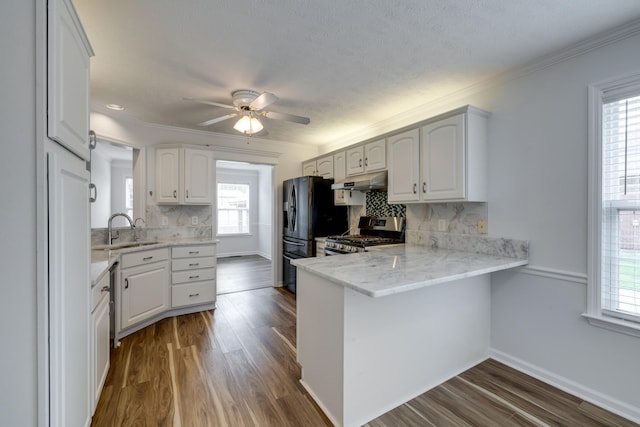 3216 Vestry Ave, Murfreesboro, TN 37129 - kitchen with stainless steel gas stove, under cabinet range hood, a peninsula, backsplash, and dark wood finished floors