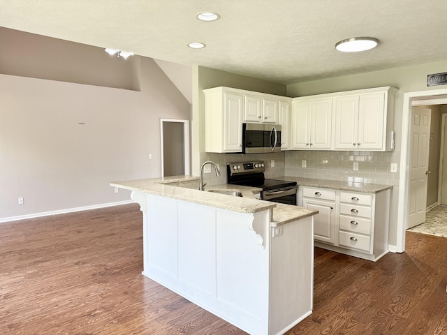 740 N Palmers Chapel Rd, White House, TN 37188 - kitchen with appliances with stainless steel finishes, a peninsula, a kitchen bar, white cabinetry, and dark wood-style floors
