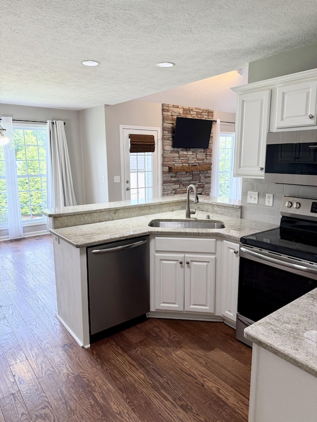 740 N Palmers Chapel Rd, White House, TN 37188 - kitchen with appliances with stainless steel finishes, dark wood-style floors, a textured ceiling, a peninsula, and white cabinetry