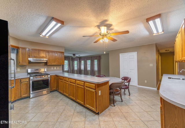100 Cusick Cir, Lenoir City, TN 37772 - kitchen with stainless steel range with gas cooktop, under cabinet range hood, a textured ceiling, a ceiling fan, and a peninsula