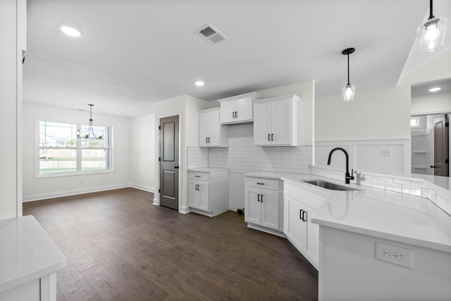1250 Elizabeth Ln, Clarksville, TN 37042 - kitchen featuring a peninsula, a chandelier, white cabinets, backsplash, and dark wood-style floors