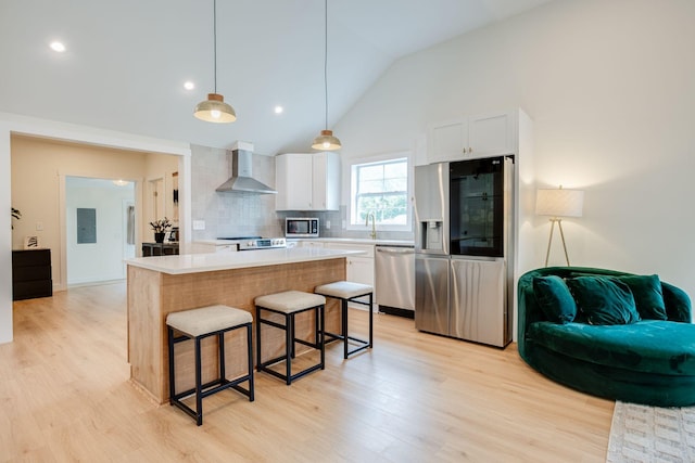 4017 Cedar Cir, Nashville, TN 37218 - kitchen with appliances with stainless steel finishes, wall chimney exhaust hood, a breakfast bar area, white cabinets, and light wood-type flooring