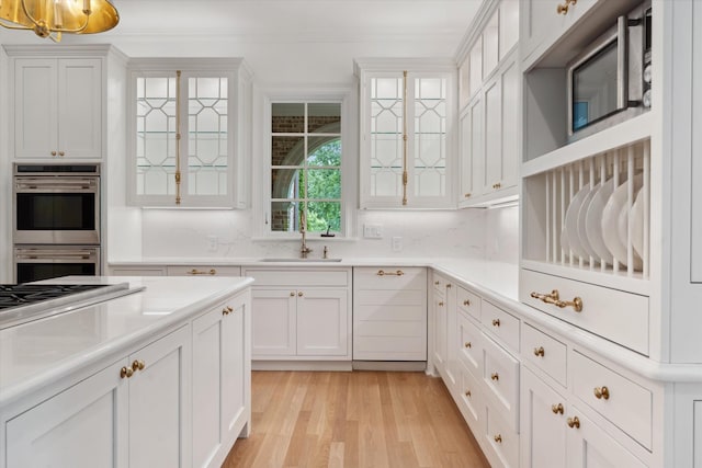 2455 Hidden River Ln, Franklin, TN 37069 - kitchen featuring appliances with stainless steel finishes, white cabinetry, light wood finished floors, and glass insert cabinets