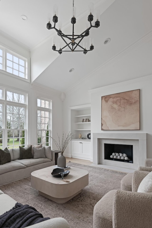 2455 Hidden River Ln, Franklin, TN 37069 - living room featuring a chandelier, built in shelves, a fireplace, high vaulted ceiling, and ornamental molding