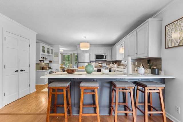 1830 Bradbury Rd, Adams, TN 37010 - kitchen with stainless steel appliances, a peninsula, light wood-style flooring, decorative backsplash, and light countertops