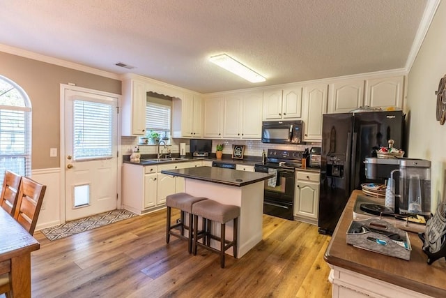 1699 Burnt Oak Dr Unit 195, Dalton, GA 30721 - kitchen featuring black appliances, light wood finished floors, dark countertops, ornamental molding, and a textured ceiling