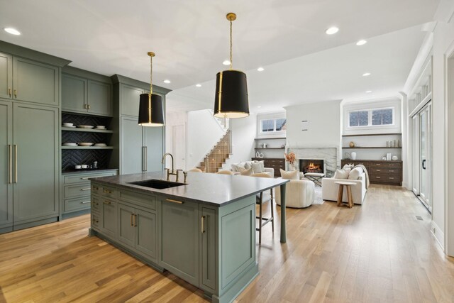 8876 Edgecomb Dr, College Grove, TN 37046 - kitchen featuring green cabinets, light wood finished floors, a fireplace, a kitchen island with sink, and recessed lighting