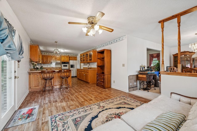 8663 Dog Branch Rd, Mount Pleasant, TN 38474 - living room with a ceiling fan, light wood-style flooring, a chandelier, and a textured ceiling