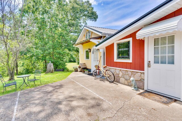 997 W 12th St, Chickamauga, GA 30707 - view of exterior entry featuring stone siding, a metal roof, a lawn, and a patio