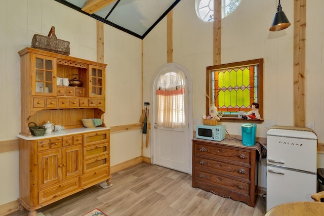 997 W 12th St, Chickamauga, GA 30707 - kitchen with white appliances, light wood-type flooring, high vaulted ceiling, glass insert cabinets, and light countertops