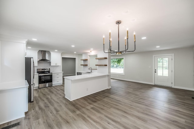 3046 Patton Branch Rd, Goodlettsville, TN 37072 - kitchen featuring appliances with stainless steel finishes, wall chimney exhaust hood, open shelves, light wood-style flooring, and a chandelier