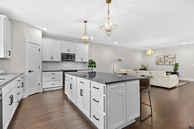 1227 N Avondale Cir, Nashville, TN 37207 - kitchen featuring stainless steel microwave, open floor plan, a kitchen island, decorative backsplash, and dark wood-style flooring