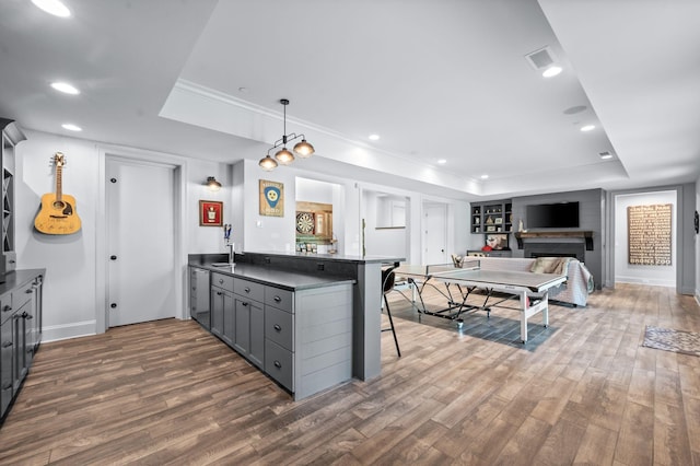 1542 Amesbury Ln, Franklin, TN 37069 - kitchen featuring a tray ceiling, a peninsula, dark wood-style flooring, gray cabinetry, and crown molding