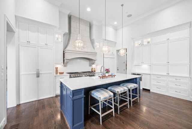 1542 Amesbury Ln, Franklin, TN 37069 - kitchen featuring white cabinetry, ornamental molding, light countertops, glass insert cabinets, and a center island with sink