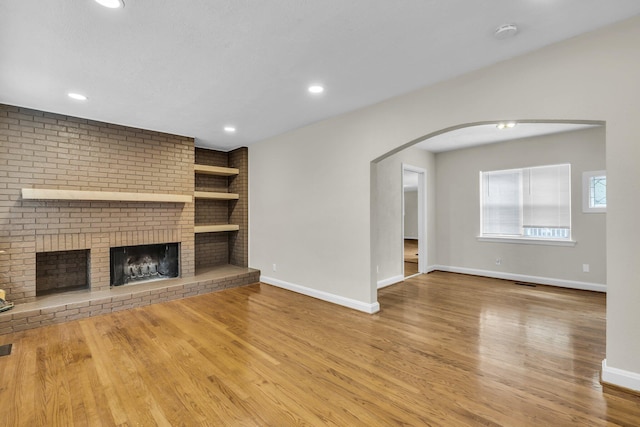 702 Marlboro Ave, Chattanooga, TN 37412 - unfurnished living room featuring wood finished floors, built in features, a fireplace, arched walkways, and recessed lighting