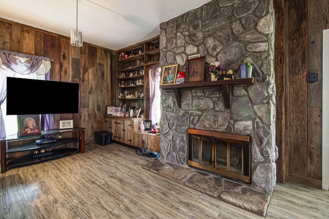 431 Haddon Ln, Winchester, TN 37398 - unfurnished living room featuring wooden walls, wood finished floors, a stone fireplace, a textured ceiling, and built in features