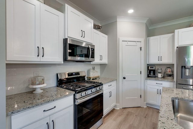 588 Davis Valley Dr, Columbia, TN 38401 - kitchen with stainless steel appliances, ornamental molding, tasteful backsplash, white cabinetry, and light wood finished floors