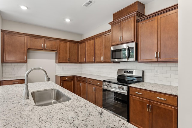 15 Aurora Cir, Fayetteville, TN 37334 - kitchen featuring stainless steel appliances, light stone countertops, backsplash, recessed lighting, and brown cabinetry