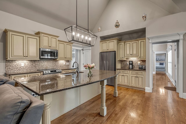 122 Ridgebend Dr, Murfreesboro, TN 37128 - kitchen featuring cream cabinetry, appliances with stainless steel finishes, open floor plan, a kitchen breakfast bar, and decorative backsplash