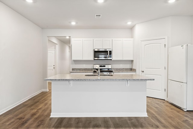 8044 Typhani Way, White House, TN 37188 - kitchen with appliances with stainless steel finishes, a kitchen island with sink, light stone countertops, white cabinetry, and wood finished floors