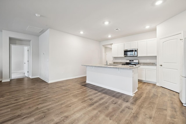 8044 Typhani Way, White House, TN 37188 - kitchen with appliances with stainless steel finishes, recessed lighting, white cabinetry, a kitchen island with sink, and light wood finished floors