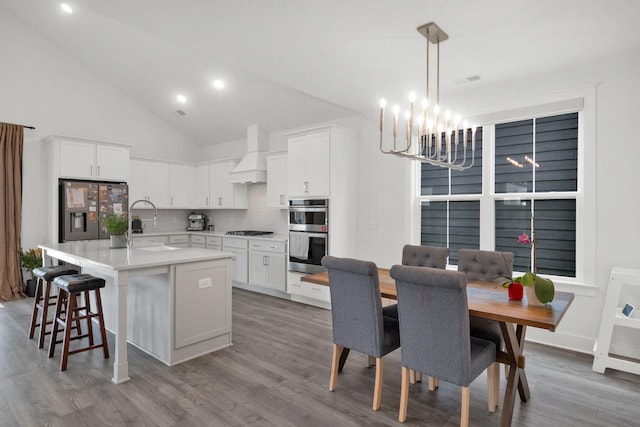 373 Hammock Ln, Spring Hill, TN 37174 - kitchen featuring appliances with stainless steel finishes, a chandelier, custom range hood, tasteful backsplash, and a breakfast bar
