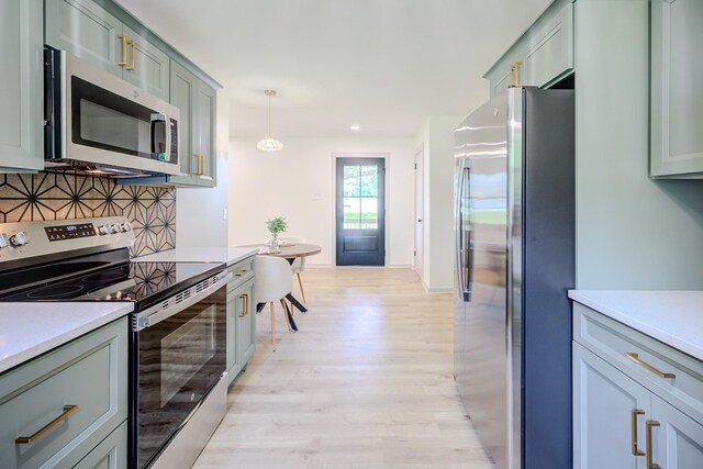 445 High Point Rd, Clarksville, TN 37042 - kitchen featuring appliances with stainless steel finishes, light wood finished floors, light countertops, backsplash, and hanging light fixtures