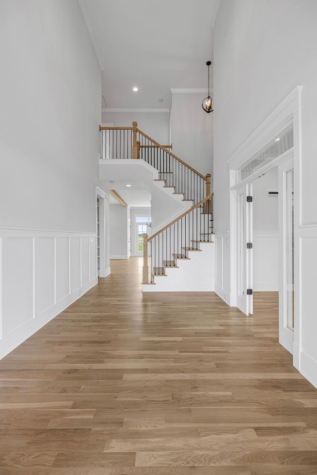 5937 Hunt Valley Dr, Spring Hill, TN 37174 - unfurnished living room featuring a decorative wall, a towering ceiling, stairs, light wood-type flooring, and ornamental molding