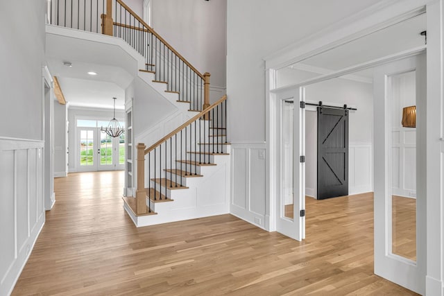 5937 Hunt Valley Dr, Spring Hill, TN 37174 - stairway with a decorative wall, a chandelier, wood finished floors, a barn door, and a high ceiling