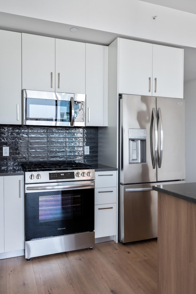 1212 Demonbreun St Unit A9 L, Nashville, TN 37203 - kitchen featuring appliances with stainless steel finishes, white cabinetry, backsplash, and light wood finished floors