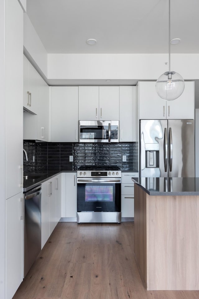 1212 Demonbreun St Unit A9 L, Nashville, TN 37203 - kitchen with stainless steel appliances, dark countertops, backsplash, and white cabinetry