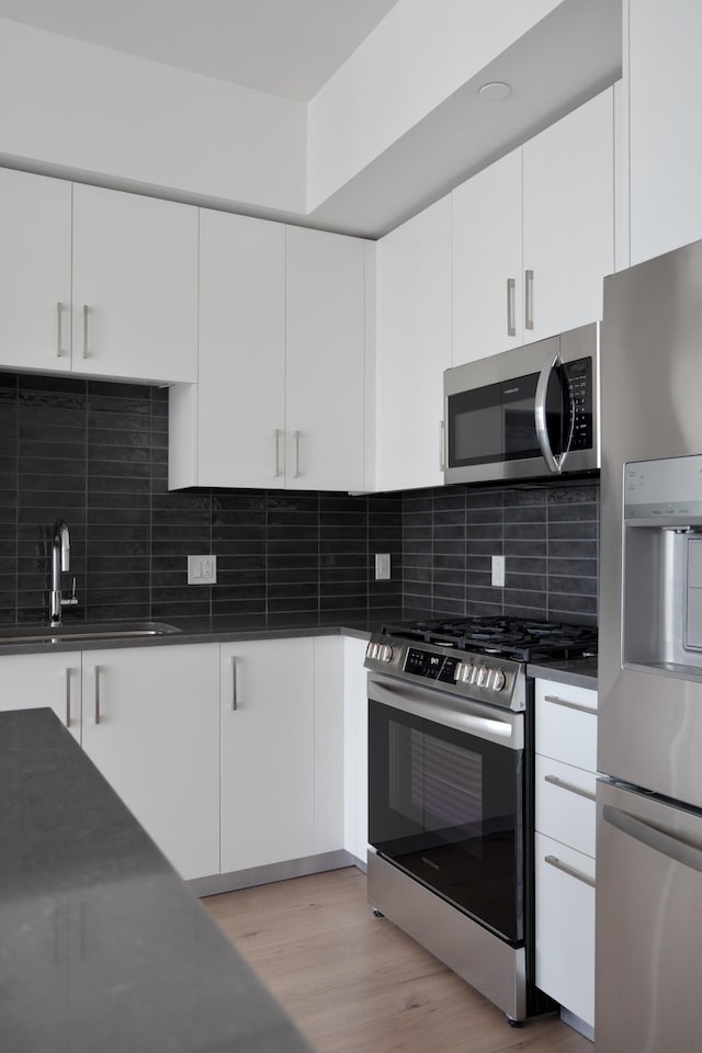 1212 Demonbreun St Unit A9 L, Nashville, TN 37203 - kitchen featuring stainless steel appliances, dark countertops, light wood-type flooring, and white cabinetry