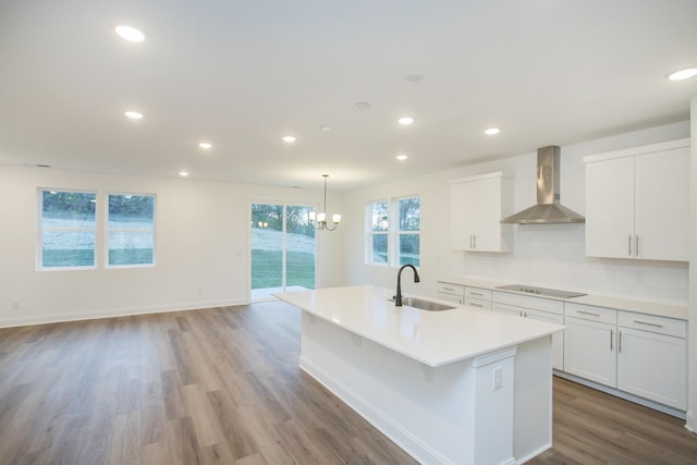 2322 Williamsport Lndg, Columbia, TN 38401 - kitchen with wall chimney exhaust hood, black electric stovetop, an island with sink, light wood finished floors, and light countertops