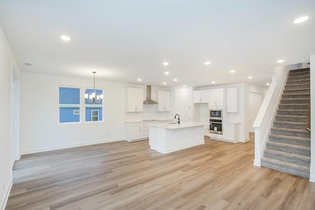 2322 Williamsport Lndg, Columbia, TN 38401 - kitchen with wall chimney exhaust hood, built in microwave, light wood-style flooring, white cabinets, and a chandelier