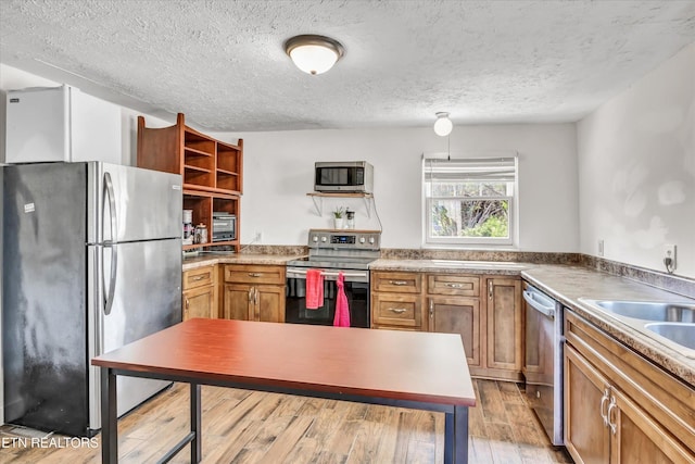 4616 Coile Rd, Knoxville, TN 37918 - kitchen featuring appliances with stainless steel finishes, open shelves, light wood-style floors, brown cabinets, and a textured ceiling