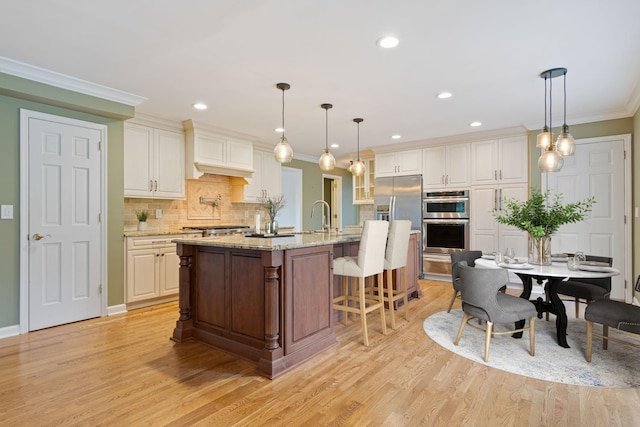 1111 Chickasaw Dr, Brentwood, TN 37027 - kitchen with double oven, light wood-style flooring, crown molding, decorative backsplash, and a kitchen breakfast bar