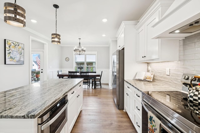 1037 Jackston Mack Way, Gallatin, TN 37066 - kitchen featuring appliances with stainless steel finishes, premium range hood, white cabinetry, light stone countertops, and wainscoting