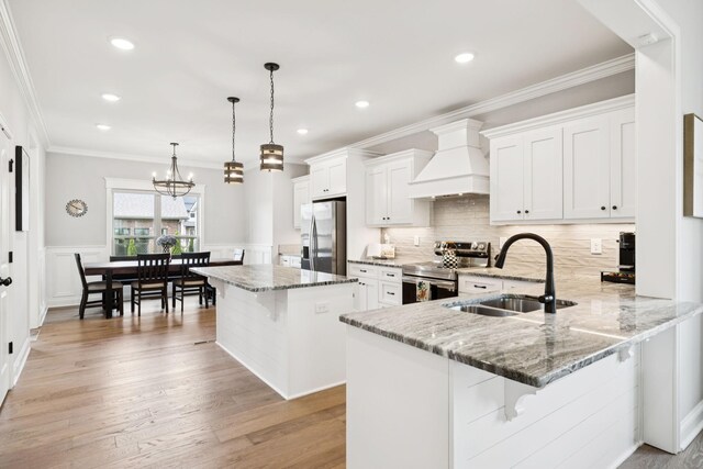 1037 Jackston Mack Way, Gallatin, TN 37066 - kitchen with stainless steel appliances, custom exhaust hood, a kitchen bar, white cabinetry, and wainscoting