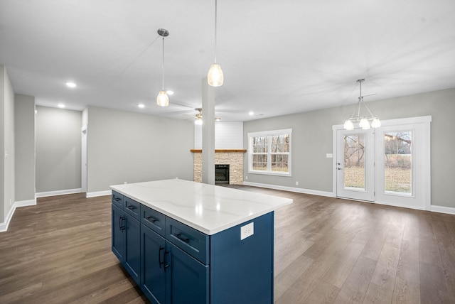 108 Hummingbird Way, Clarksville, TN 37043 - kitchen with blue cabinets, dark wood finished floors, a stone fireplace, a kitchen island, and a ceiling fan