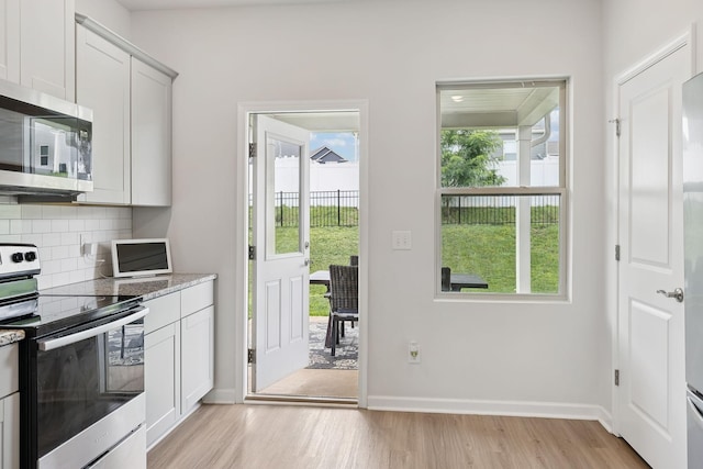 3276 Holiday Ln, Columbia, TN 38401 - kitchen featuring appliances with stainless steel finishes, light wood-style flooring, decorative backsplash, light stone countertops, and white cabinetry