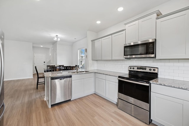 3276 Holiday Ln, Columbia, TN 38401 - kitchen featuring stainless steel appliances, light wood-type flooring, backsplash, a peninsula, and recessed lighting