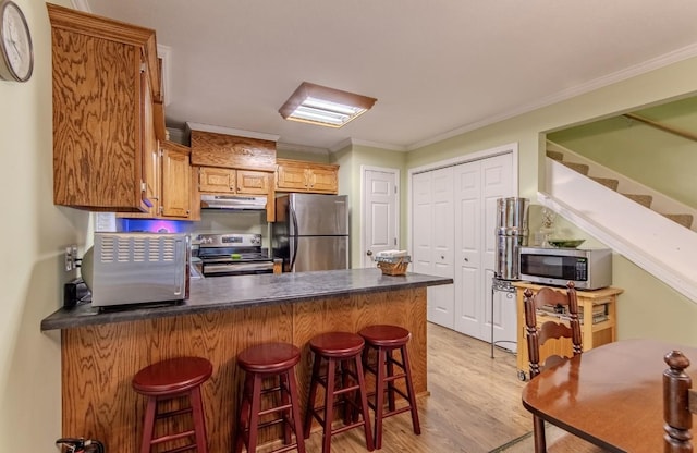 730 Carlew Rd, Waynesboro, TN 38485 - kitchen with appliances with stainless steel finishes, under cabinet range hood, a peninsula, light wood-style flooring, and crown molding