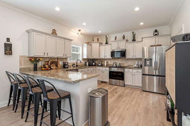 2018 Via Francesco Ct, Spring Hill, TN 37174 - kitchen with appliances with stainless steel finishes, a peninsula, crown molding, light stone countertops, and light wood-style floors