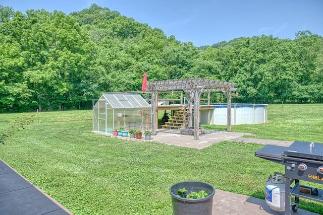 1034 Gaw Branch Rd, Gainesboro, TN 38562 - view of green lawn with an exterior structure, a pergola, an outdoor pool, an outdoor structure, and a wooded view